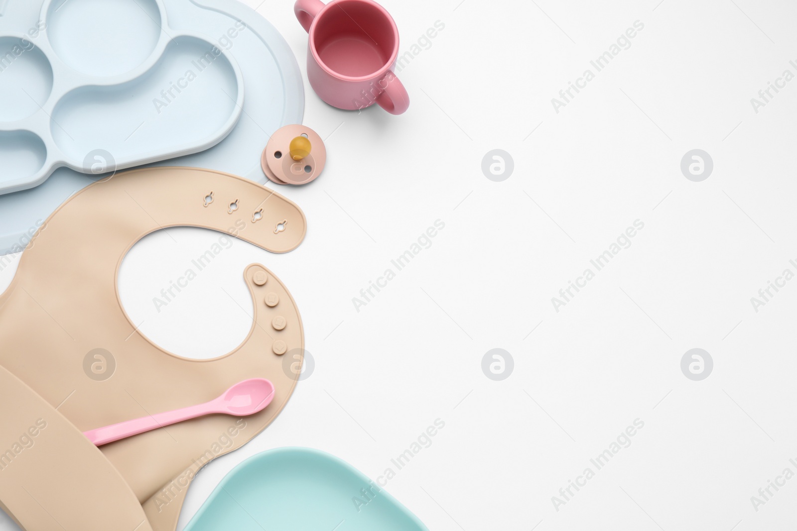 Photo of Composition with baby feeding accessories and bib on white background, top view. Space for text