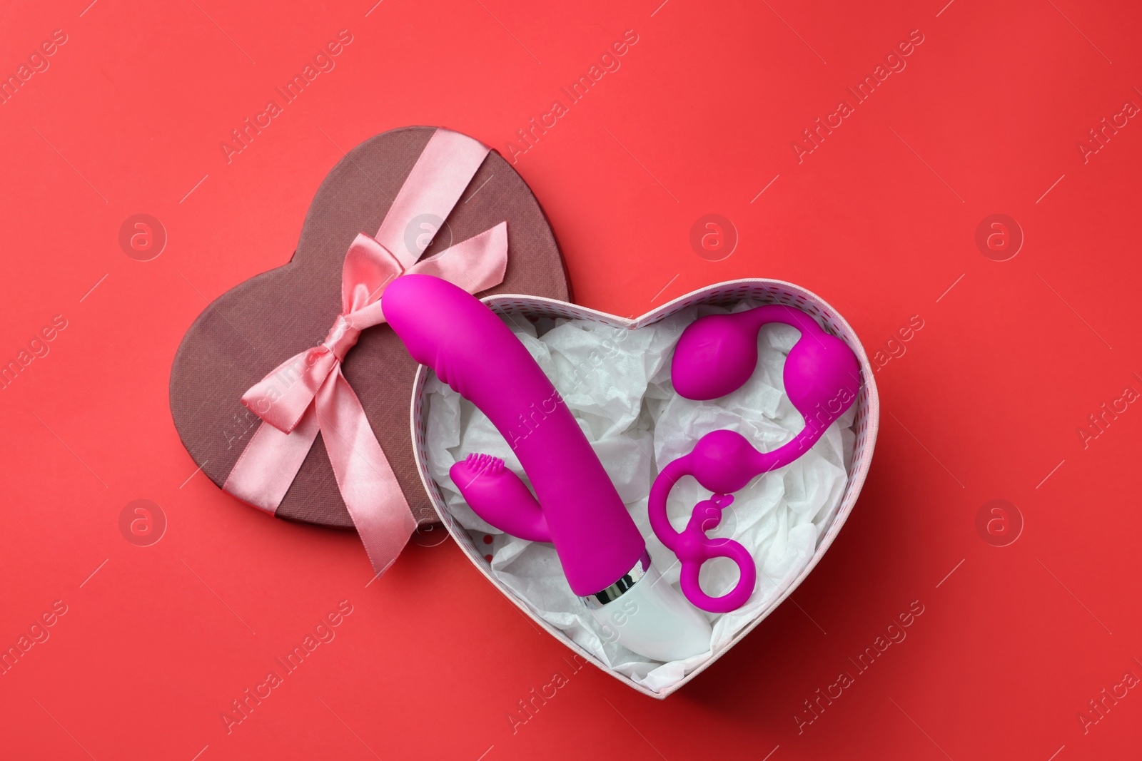 Photo of Gift box with sex toys on red background, top view. Space for text