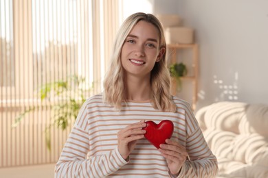 Photo of Happy volunteer holding red heart with hands indoors