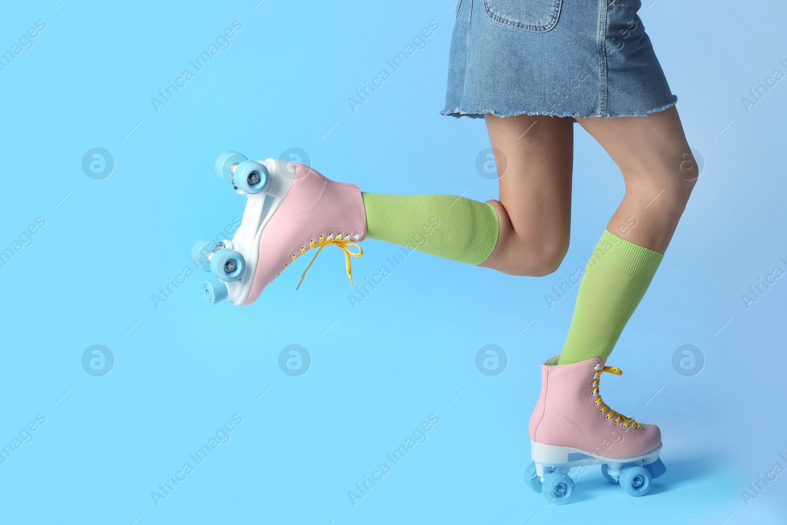 Photo of Woman with vintage roller skates on color background, closeup