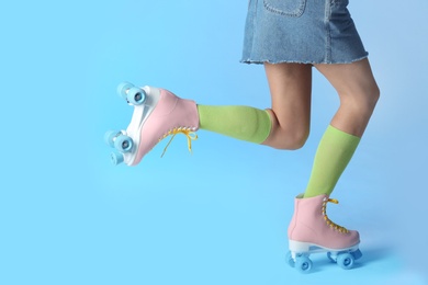 Photo of Woman with vintage roller skates on color background, closeup