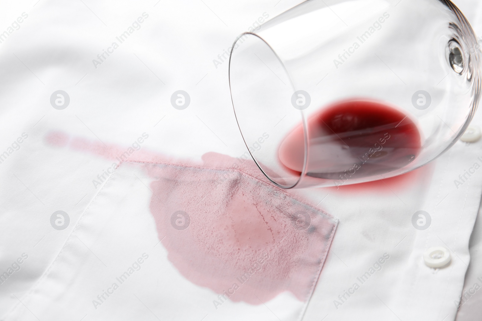 Photo of Overturned glass and spilled exquisite red wine on white shirt. Space for text