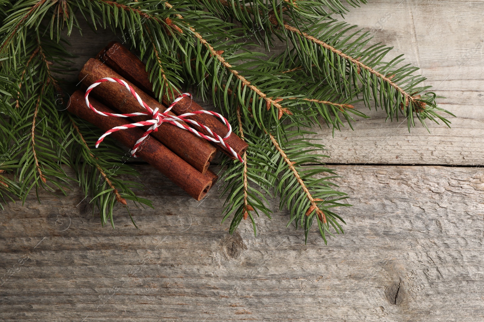 Photo of Cinnamon sticks and fir branches on wooden table, flat lay