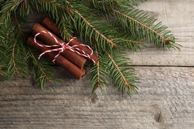 Photo of Cinnamon sticks and fir branches on wooden table, flat lay