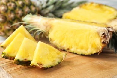 Photo of Cut fresh juicy pineapple on wooden board, closeup