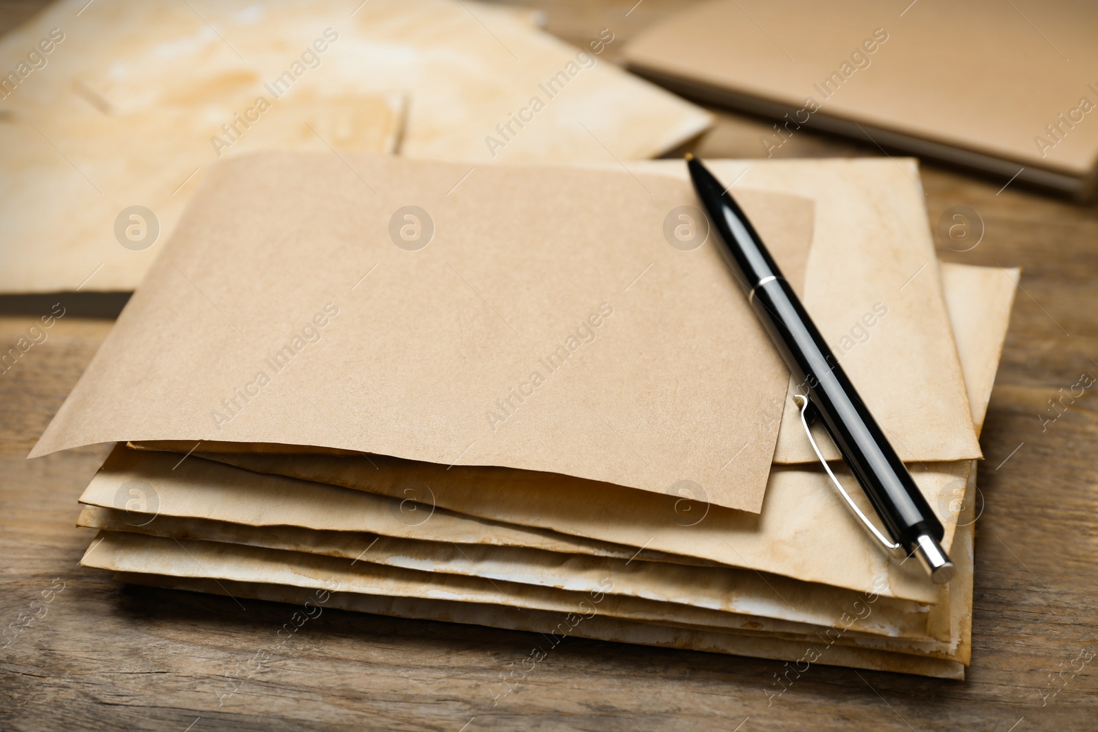 Photo of Stack of old letters with pen on wooden table, closeup