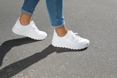 Woman in stylish sneakers walking outdoors, focus on legs