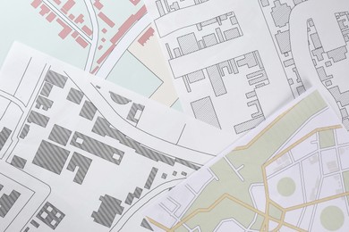 Photo of Many different cadastral maps of territory with buildings as background, top view