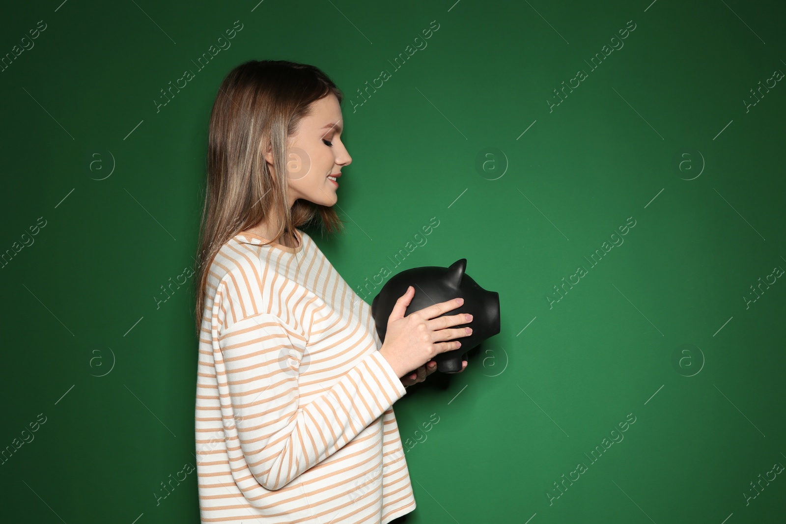Photo of Young woman with piggy bank on color background. Space for text