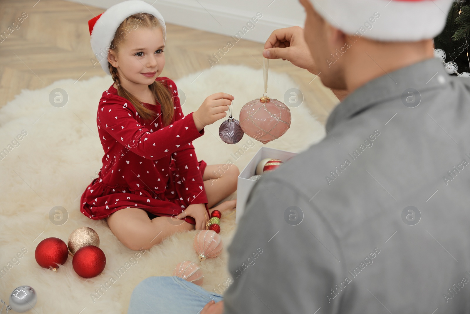 Photo of Father with his cute daughter decorating Christmas tree together indoors