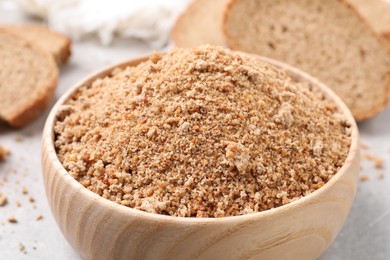 Photo of Fresh bread crumbs in bowl on grey table, closeup