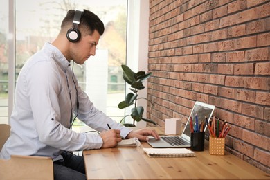 Photo of Man drawing in notebook at online lesson indoors. Distance learning