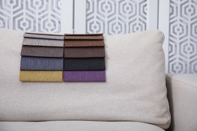 Photo of Catalog of colorful fabric samples on beige sofa indoors