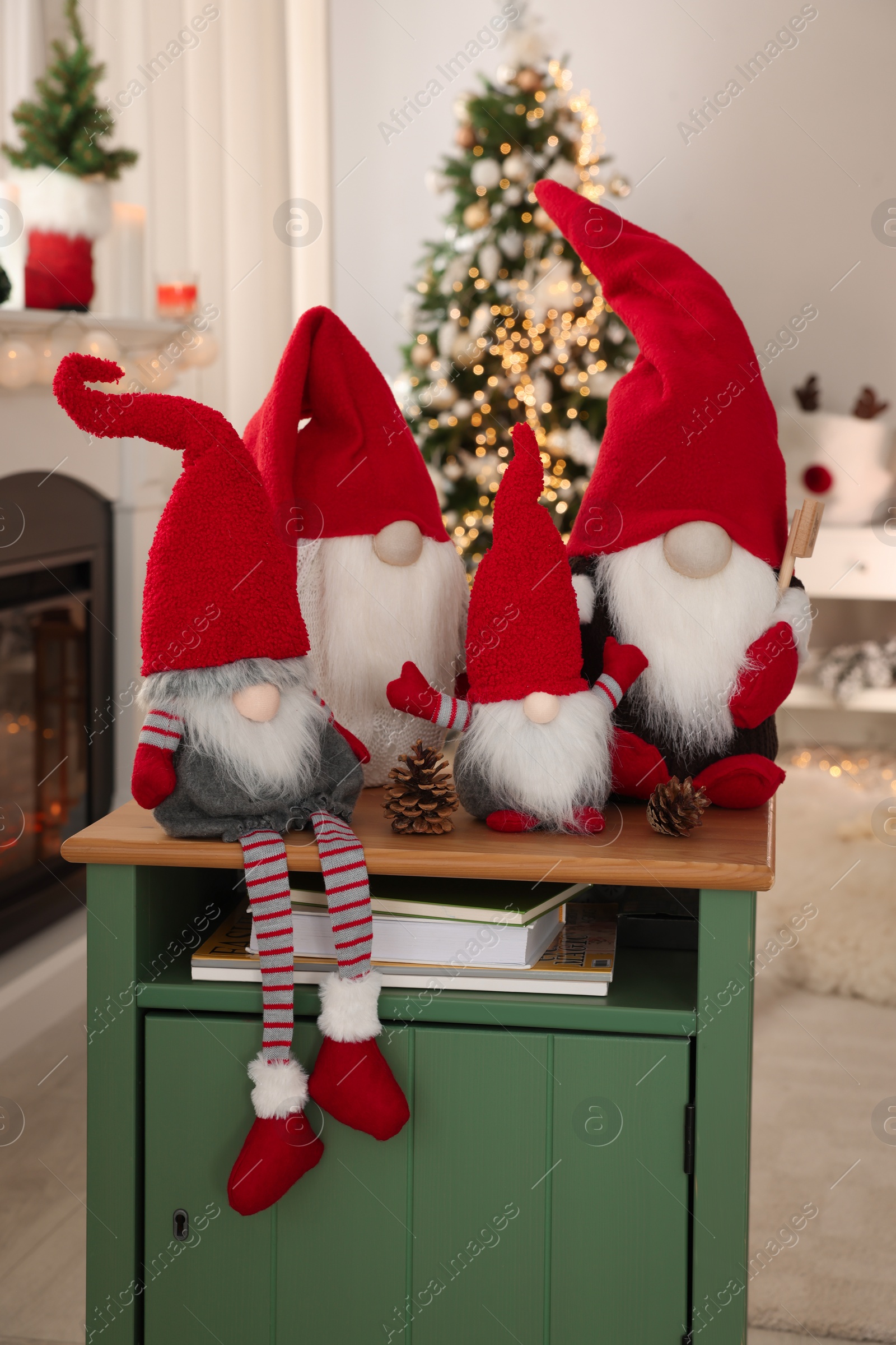 Photo of Cute Christmas gnomes on wooden table in room with festive decorations