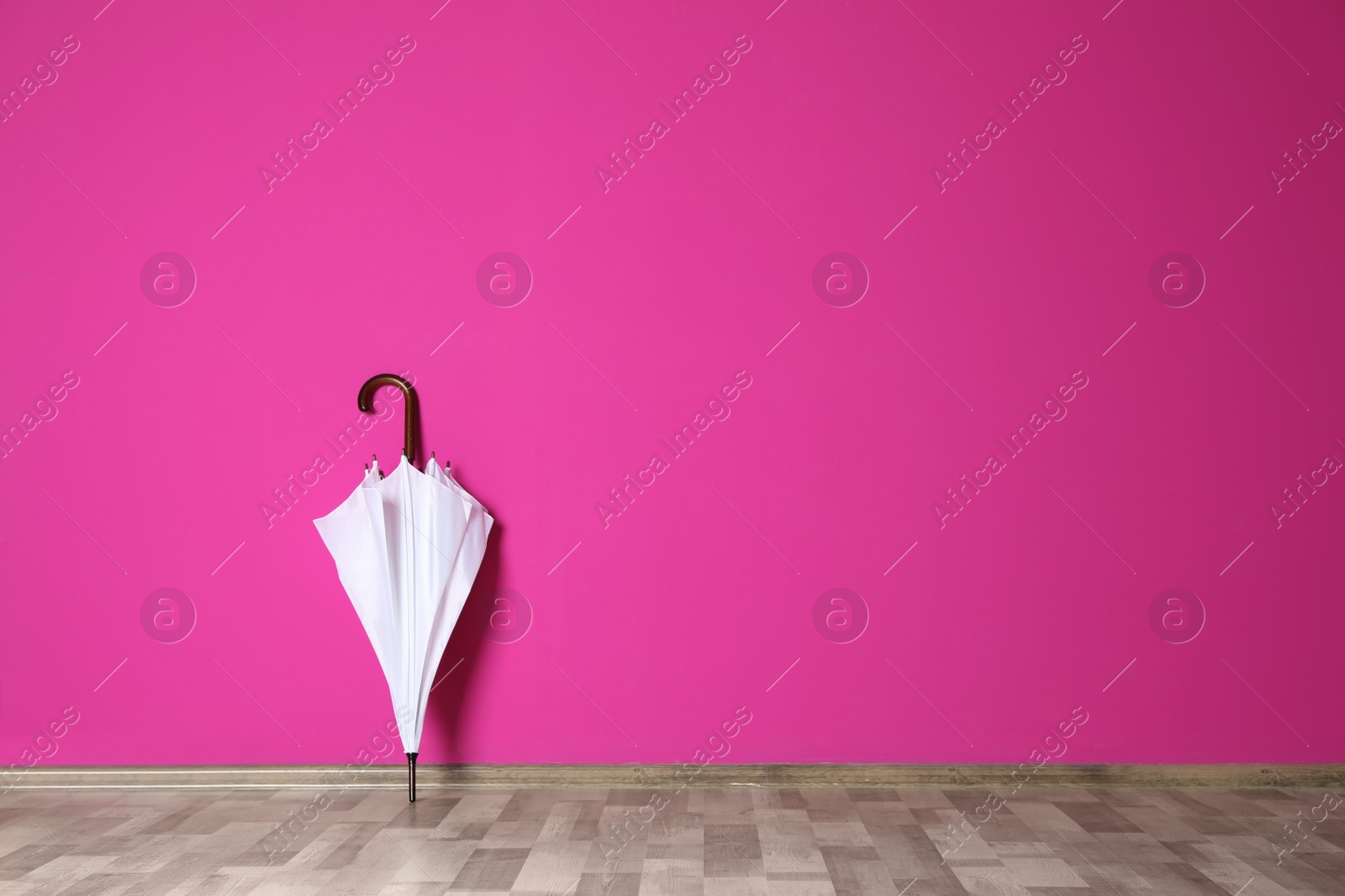 Photo of Beautiful umbrella on floor near color wall with space for design