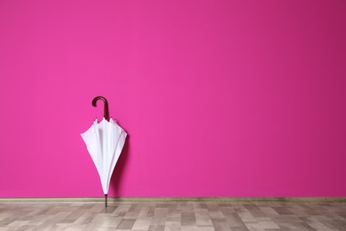 Photo of Beautiful umbrella on floor near color wall with space for design