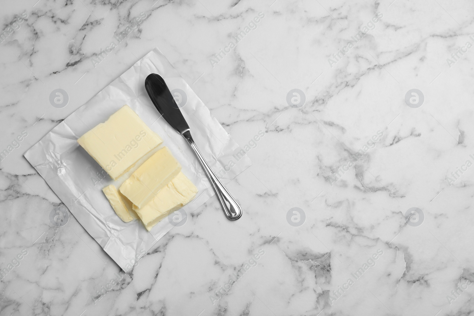 Photo of Tasty fresh butter and knife on table, top view