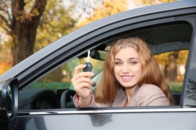 Photo of Happy woman holding car key in auto. Driving license test