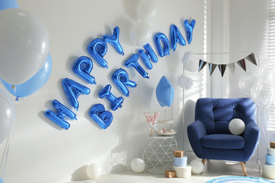 Photo of Phrase HAPPY BIRTHDAY made of blue balloon letters in decorated room