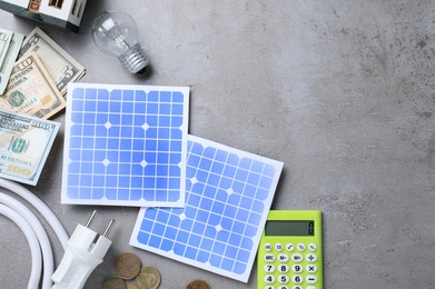 Photo of Flat lay composition with solar panels and money on grey table. Space for text
