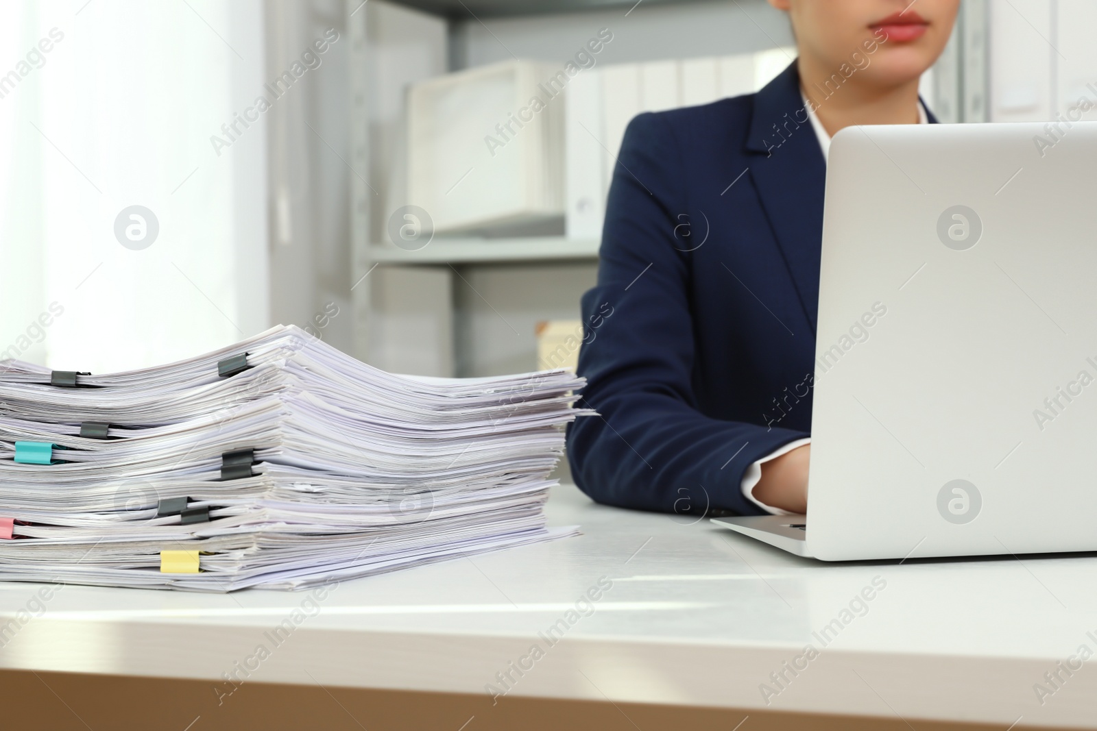 Photo of Female worker working with laptop near stack of documents in office, closeup