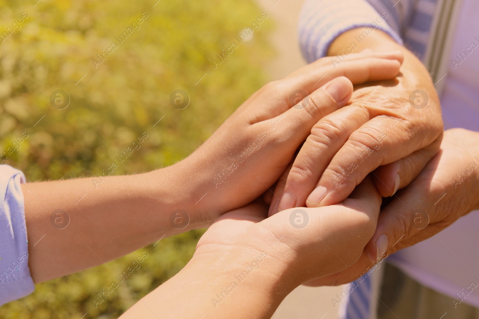 Photo of Helping hands on blurred background, closeup. Elderly care concept