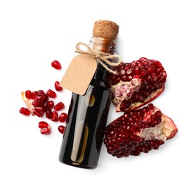 Photo of Bottle of pomegranate sauce and fresh ripe fruit on white background, top view