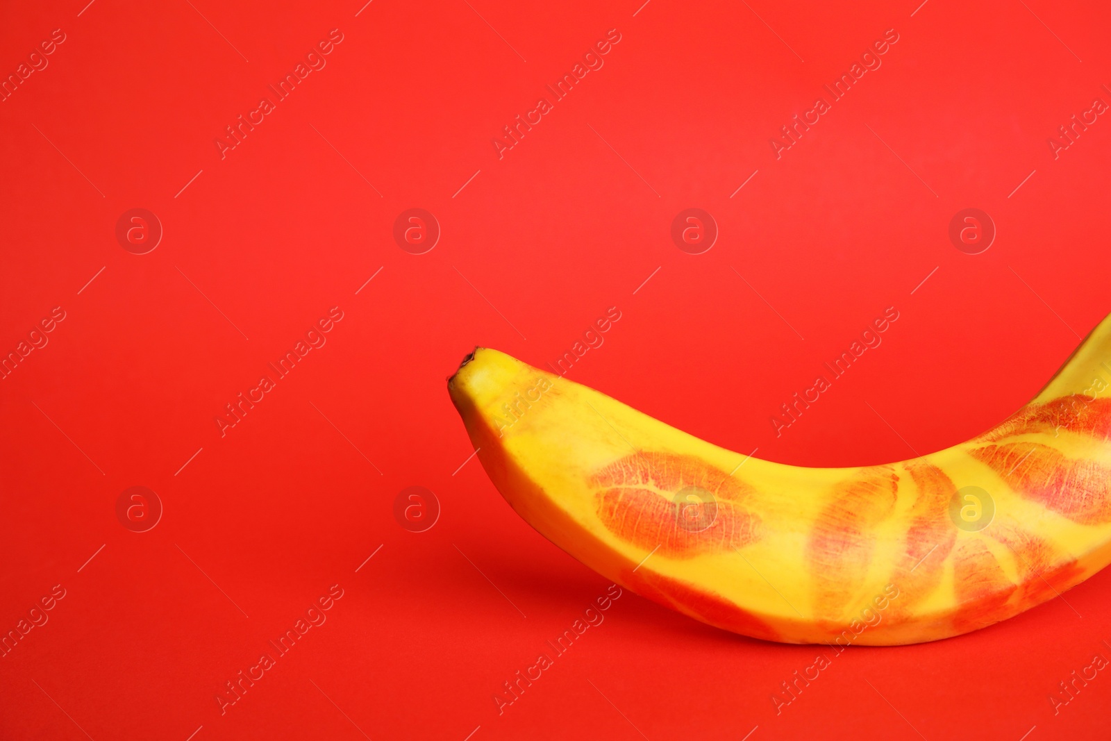 Photo of Fresh banana with lipstick marks on red background, space for text. Oral sex concept