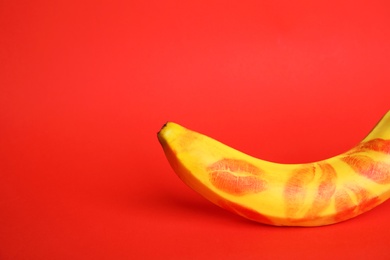 Fresh banana with lipstick marks on red background, space for text. Oral sex concept