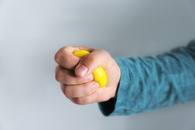 Photo of Man squeezing antistress ball on grey background, closeup