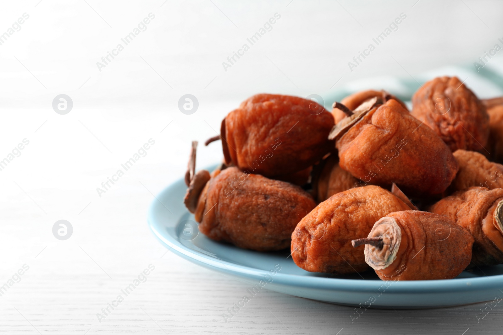 Photo of Plate with tasty dried persimmon fruits on white wooden table, closeup. Space for text