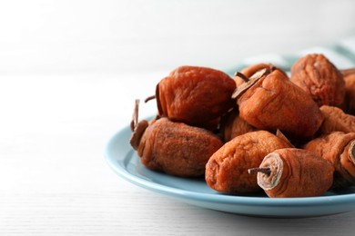 Plate with tasty dried persimmon fruits on white wooden table, closeup. Space for text