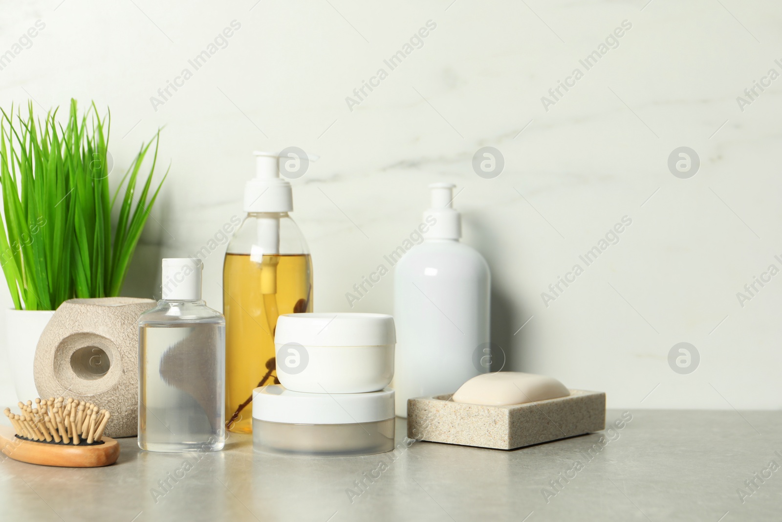 Photo of Brush and personal care products on gray table near white marble wall