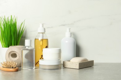 Brush and personal care products on gray table near white marble wall