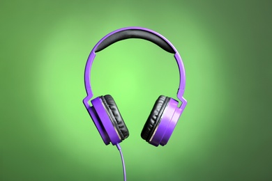 Stylish headphones with pads on color background