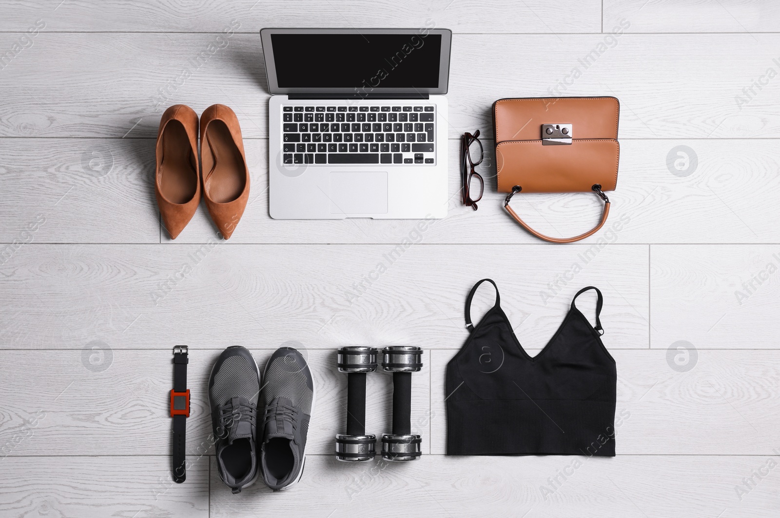 Photo of Flat lay composition with business supplies and sport equipment on white wooden floor. Concept of balance between work and life