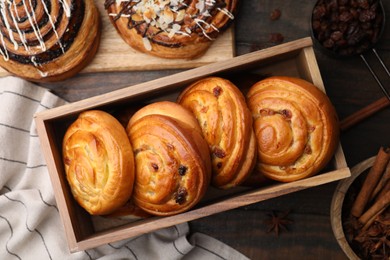 Photo of Different delicious rolls on wooden table, flat lay. Sweet buns