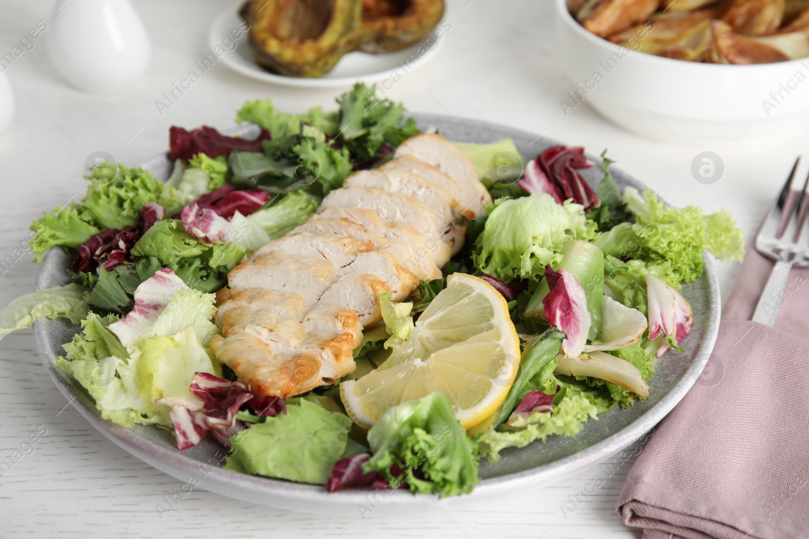 Photo of Tasty cooked chicken fillet with fresh salad served on white wooden table. Healthy meals from air fryer