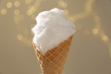 Photo of Sweet cotton candy in waffle cone against blurred lights, closeup