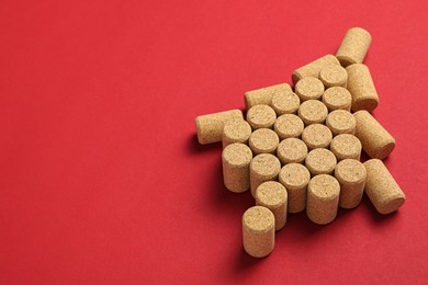 Photo of Christmas tree made of wine corks on red background. Space for text