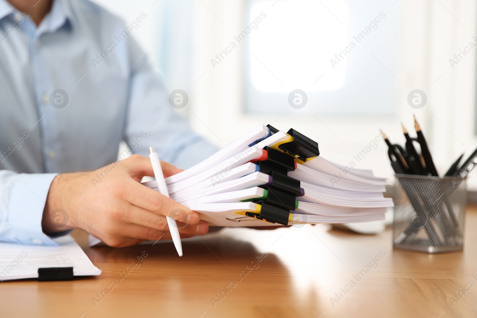 Photo of Businessman with documents at wooden table in office, closeup