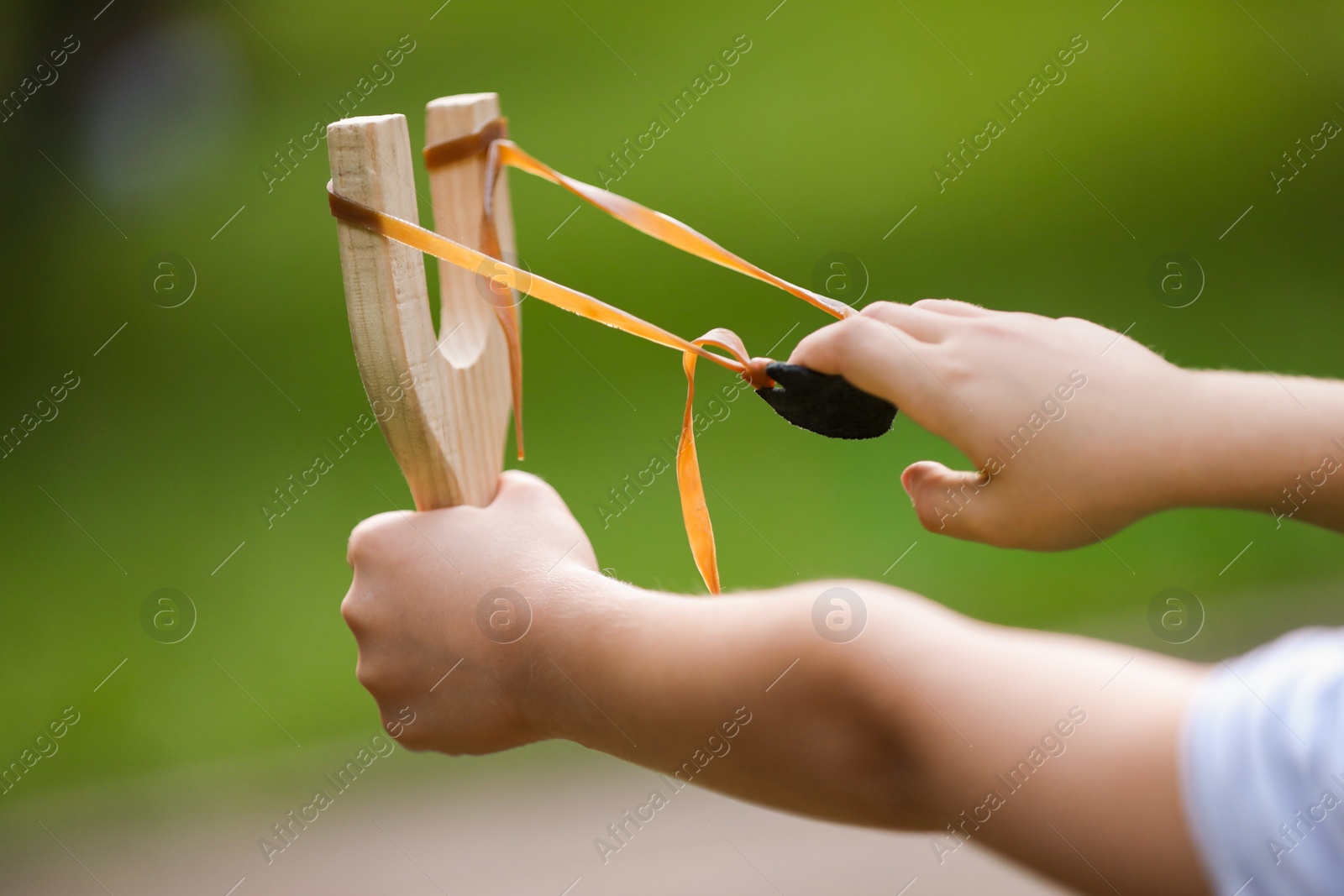 Photo of Little girl playing with slingshot outdoors, closeup