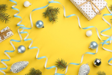 Photo of Serpentine streamers and Christmas decor on yellow background, flat lay. Space for text