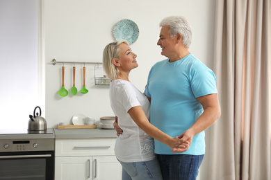 Happy mature couple dancing together in kitchen