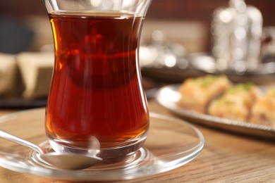 Photo of Traditional Turkish tea in glass on wooden table, closeup. Space for text