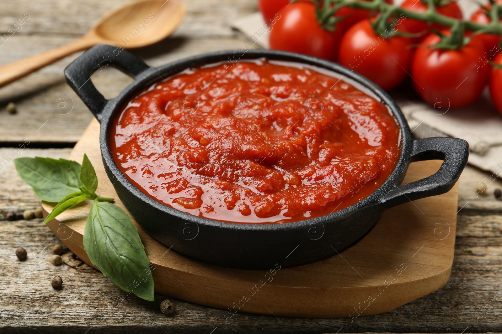 Photo of Homemade tomato sauce in bowl and basil on wooden table, closeup