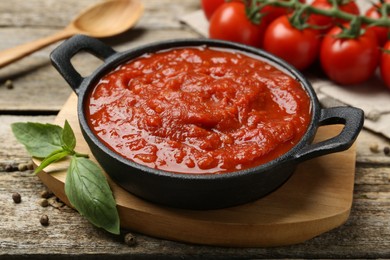 Photo of Homemade tomato sauce in bowl and basil on wooden table, closeup