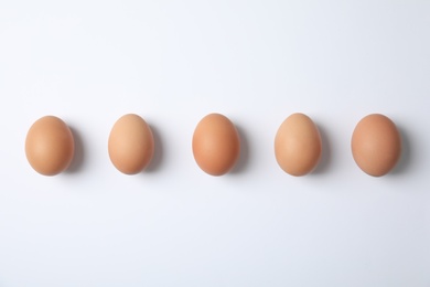 Photo of Raw chicken eggs on white background, top view