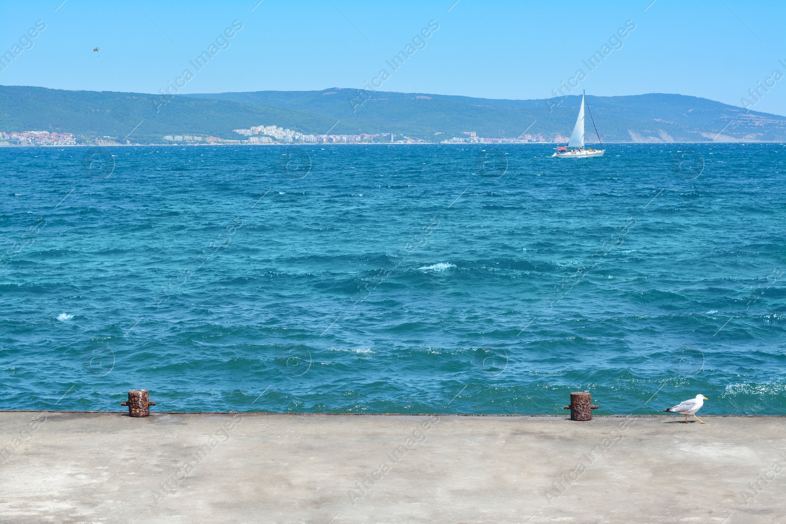 Photo of Beautiful seascape with concrete pier and sailboat on sunny day