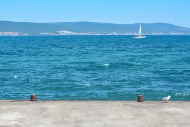 Photo of Beautiful seascape with concrete pier and sailboat on sunny day